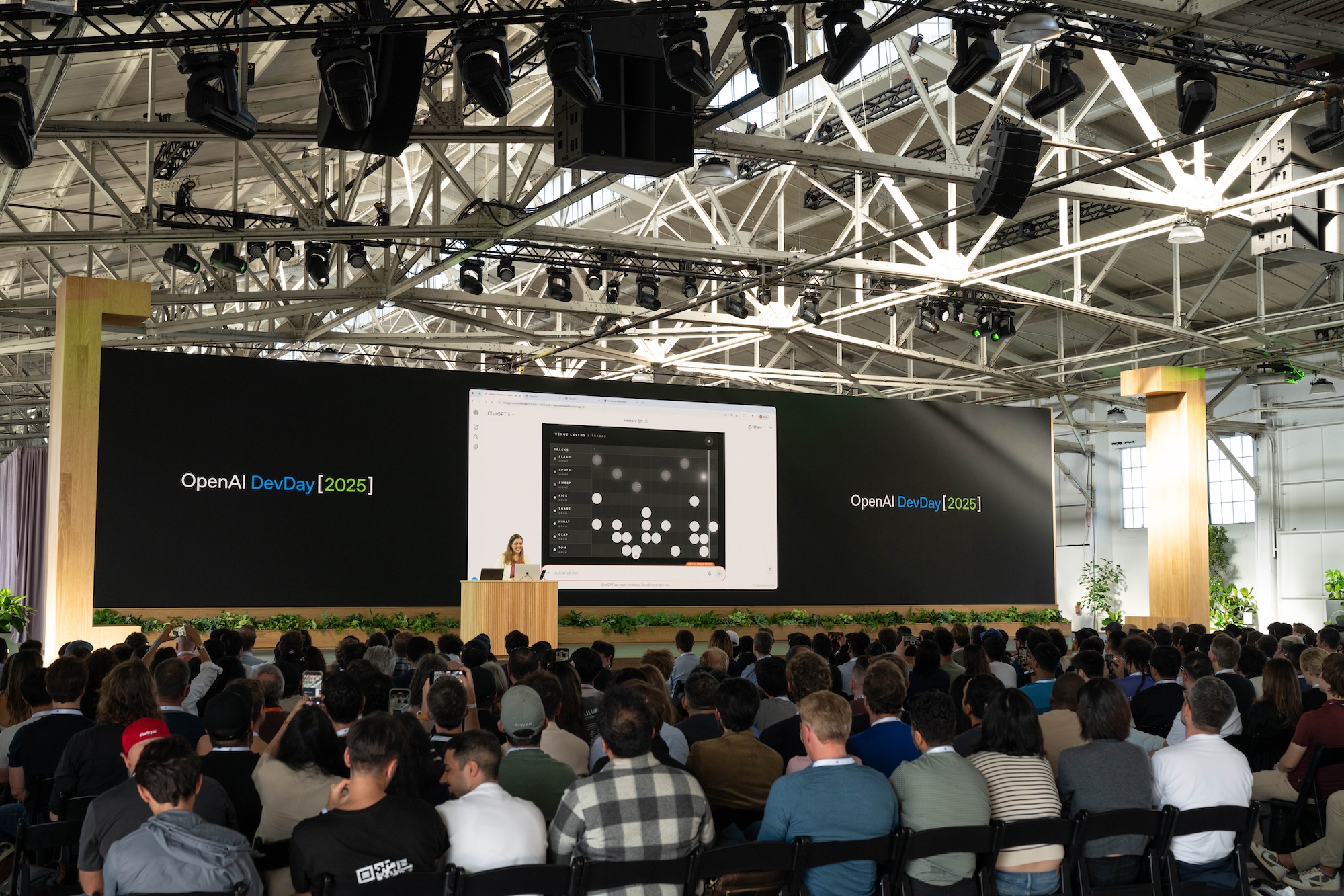 A picture of Katia on stage at DevDay 2025 with the beatpad demo running in the background